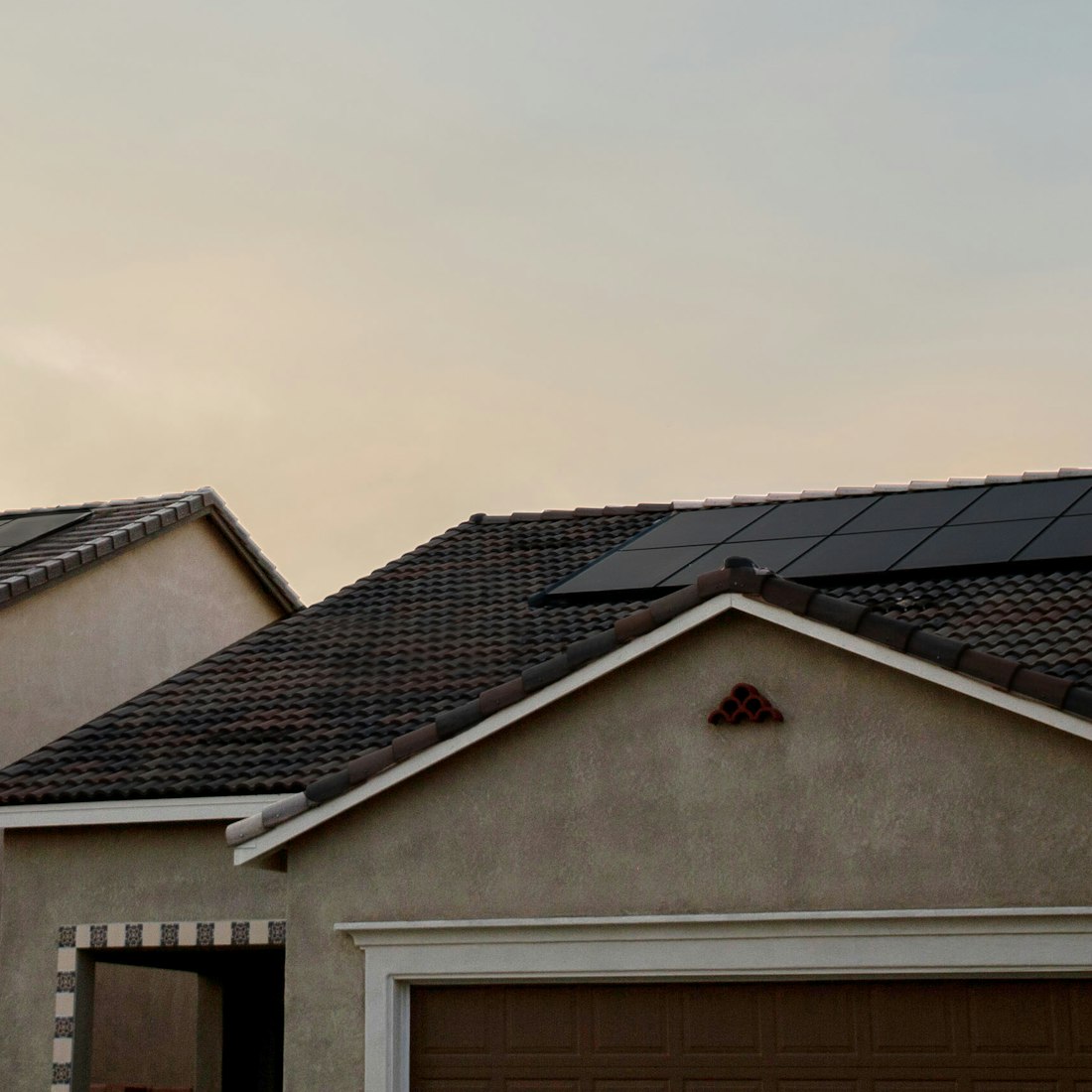 Southwest stucco homes with rooftop solar panels under a golden evening sky