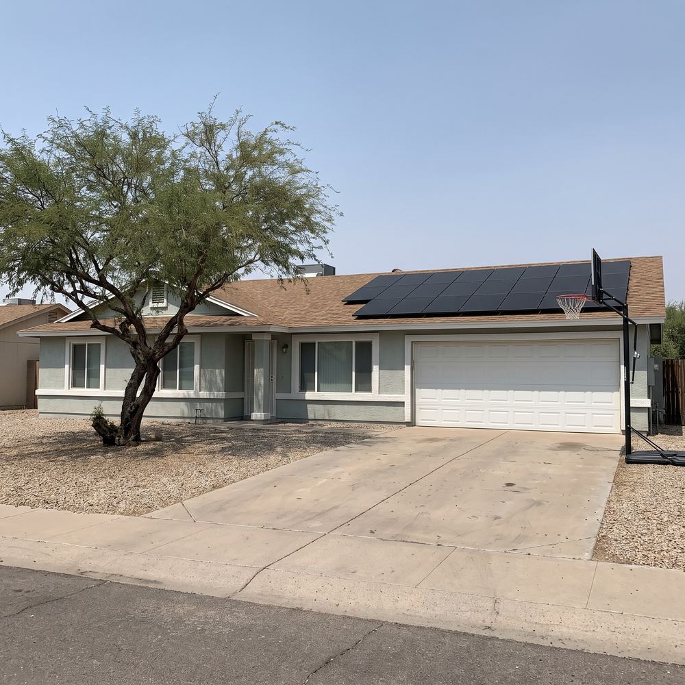 A single-story ranch home with a shingle roof and a compact rooftop solar array